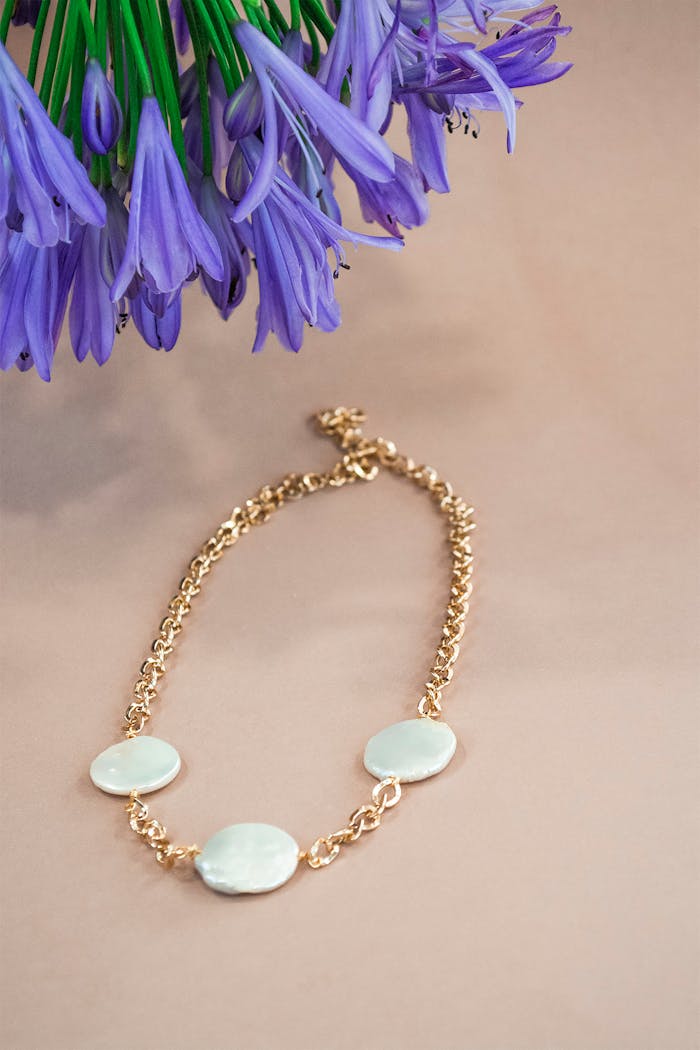 Gold necklace elegantly displayed alongside vibrant purple flowers for a luxurious look.